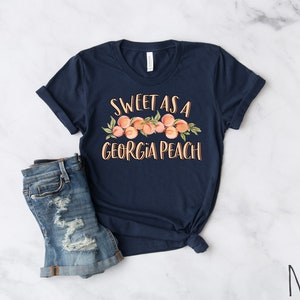 May include: Navy blue t-shirt with a peach graphic and the text "Sweet as a Georgia Peach".
