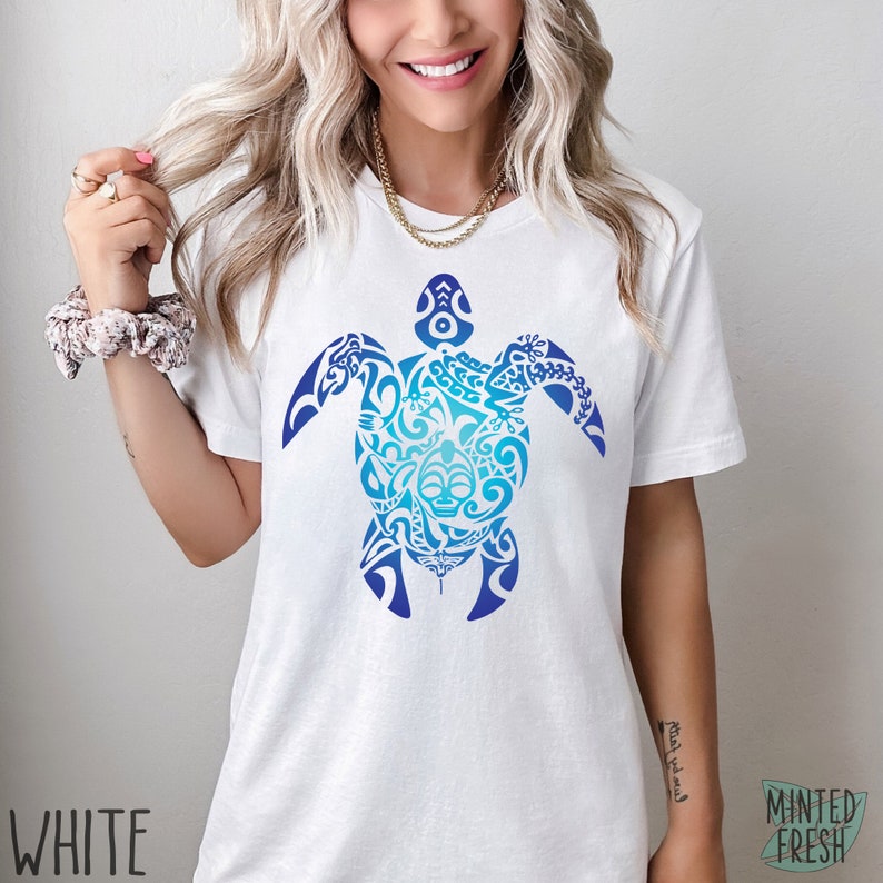 May include: White t-shirt with a blue and white gradient design of a stylized turtle with intricate patterns. The design is centered on the shirt.