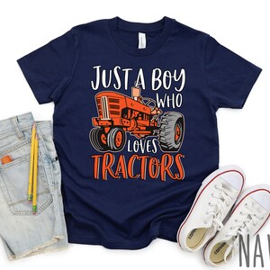 May include: A navy blue t-shirt with a red tractor graphic and the text "Just a boy who loves tractors".