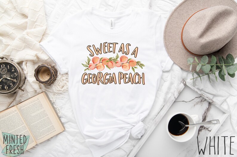 May include: White t-shirt with the text "Sweet as a Georgia Peach" and a graphic of peaches with leaves.
