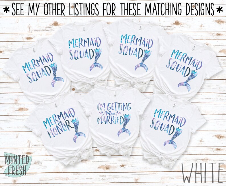 Peut inclure: Six t-shirts blancs sur le th&egrave;me de la sir&egrave;ne. Les t-shirts pr&eacute;sentent le texte "Mermaid Squad" et "Mermaid Honor" avec un graphique de queue de sir&egrave;ne. Un t-shirt dit "I'm Getting Mer-ried" avec un graphique de queue de sir&egrave;ne.
