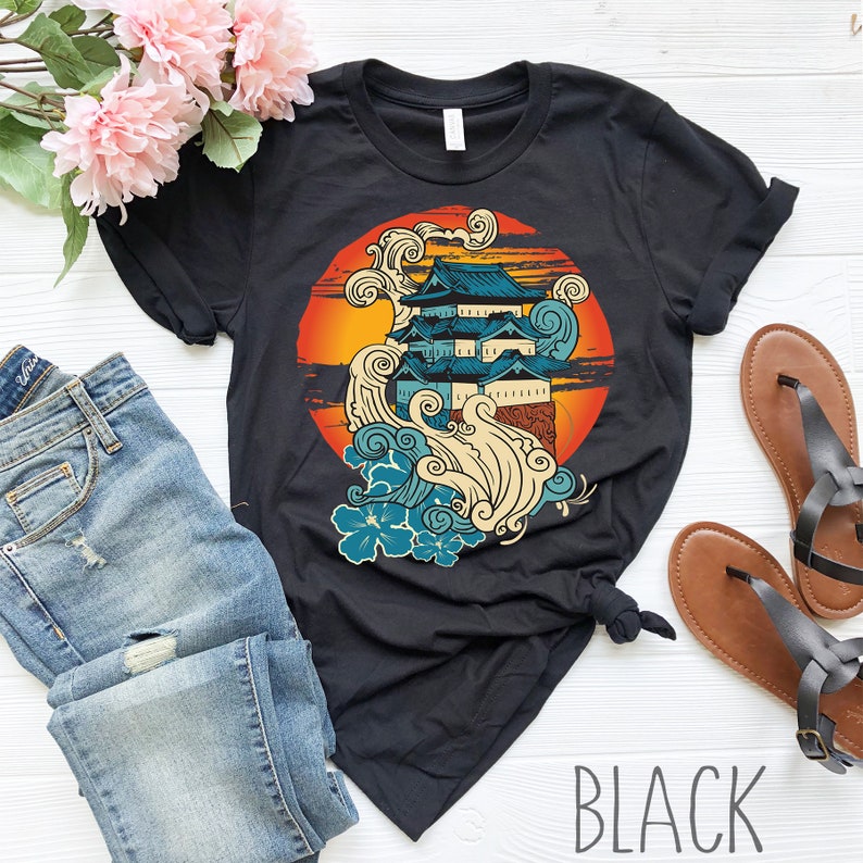 Może przedstawiać: Czarny T-shirt z nadrukiem graficznym japońskiego zamku z falami i kwiatami w k&oacute;łku. Tekst "BLACK" jest nadrukowany na dole obrazu.