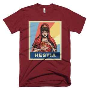 K&ouml;nnte beinhalten: Ein rotes T-Shirt mit einem Vintage-Poster-Design, das eine Frau mit roten Haaren und einem roten Kleid zeigt. Das Poster lautet "Hestia" in blauen Buchstaben.
