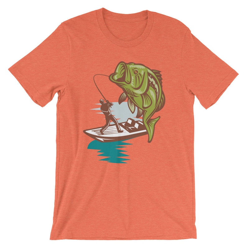 May include: A t-shirt with a graphic of a fisherman in a boat reeling in a large bass. The bass is green and brown and the boat is white with blue accents. The t-shirt is orange.