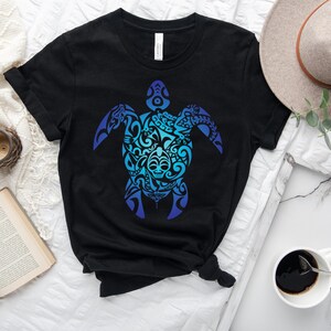 May include: Black t-shirt with a blue and teal gradient design of a stylized turtle with tribal patterns. The design is centered on the shirt.