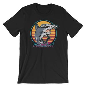 Puede incluir: Camiseta negra con un gr&aacute;fico retro de un tibur&oacute;n martillo en una puesta de sol. El texto "Hammerhead" est&aacute; impreso debajo del tibur&oacute;n.