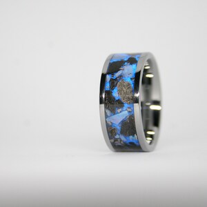 May include: A silver ring with a blue and black inlay. The inlay is made of a variety of materials, including metal and stone.