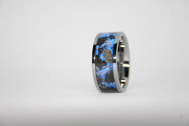 May include: A silver ring with a blue and black inlay. The inlay is made of a variety of materials, including metal and stone.