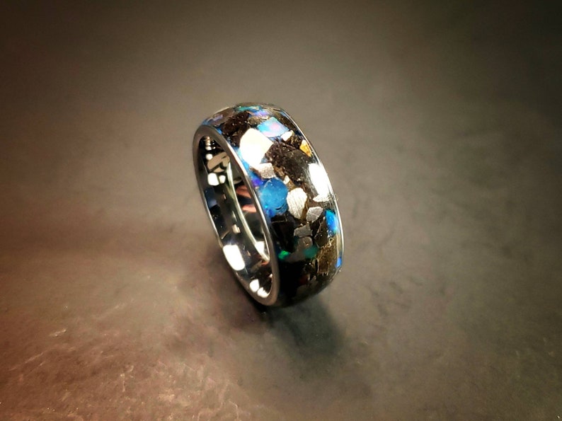 Puede incluir: Un anillo negro con una banda de virutas de &oacute;palo azul, verde y dorado iridiscentes.