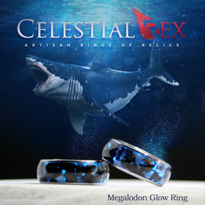 Puede incluir: Dos anillos azules y negros que brillan en la oscuridad con el texto "Megalodon Glow Ring" sobre una superficie blanca. Los anillos est&aacute;n hechos de resina y tienen un patr&oacute;n &uacute;nico y arremolinado. El fondo es una imagen borrosa de un tibur&oacute;n nadando en el oc&eacute;ano.