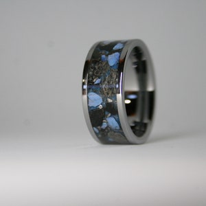 May include: A silver ring with a black and blue inlay. The inlay has a speckled pattern of blue and black.