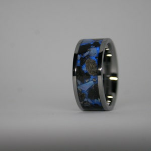May include: A black and blue ring with a unique design. The ring is made of metal and has a blue and black inlay.