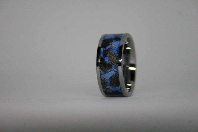 May include: A black and blue ring with a unique design. The ring is made of metal and has a blue and black inlay.