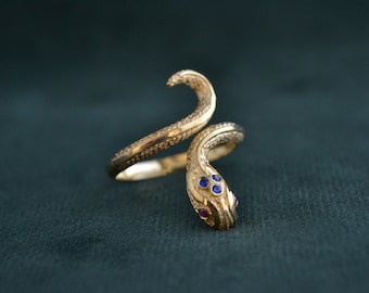 May include: A gold snake ring with blue and red gemstones for the eyes.