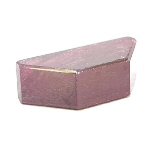 Puede incluir: Una pequeña piedra preciosa facetada con un tono magenta y púrpura intenso. La piedra presenta una forma geométrica alargada con múltiples superficies planas y pulidas que reflejan la luz, mostrando una calidad translúcida y un perfil angular.