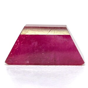 May include: A small, triangular, pink and gold resin paperweight.