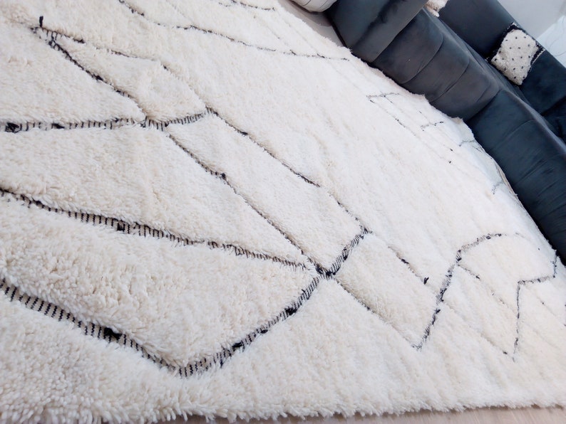May include: A white shag rug with a geometric pattern of black lines. The rug has a soft, fluffy texture.