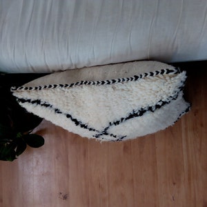 May include: White throw pillow with a black geometric pattern. The pillow is made of a fluffy, textured fabric.