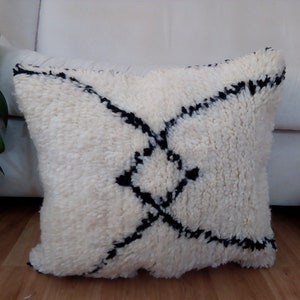 May include: White throw pillow with a black geometric pattern. The pillow is made of a soft, fluffy material.
