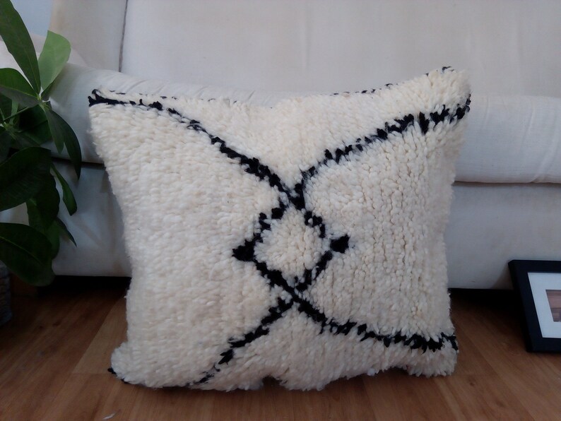May include: White throw pillow with a black geometric pattern. The pillow is made of a soft, fluffy material.