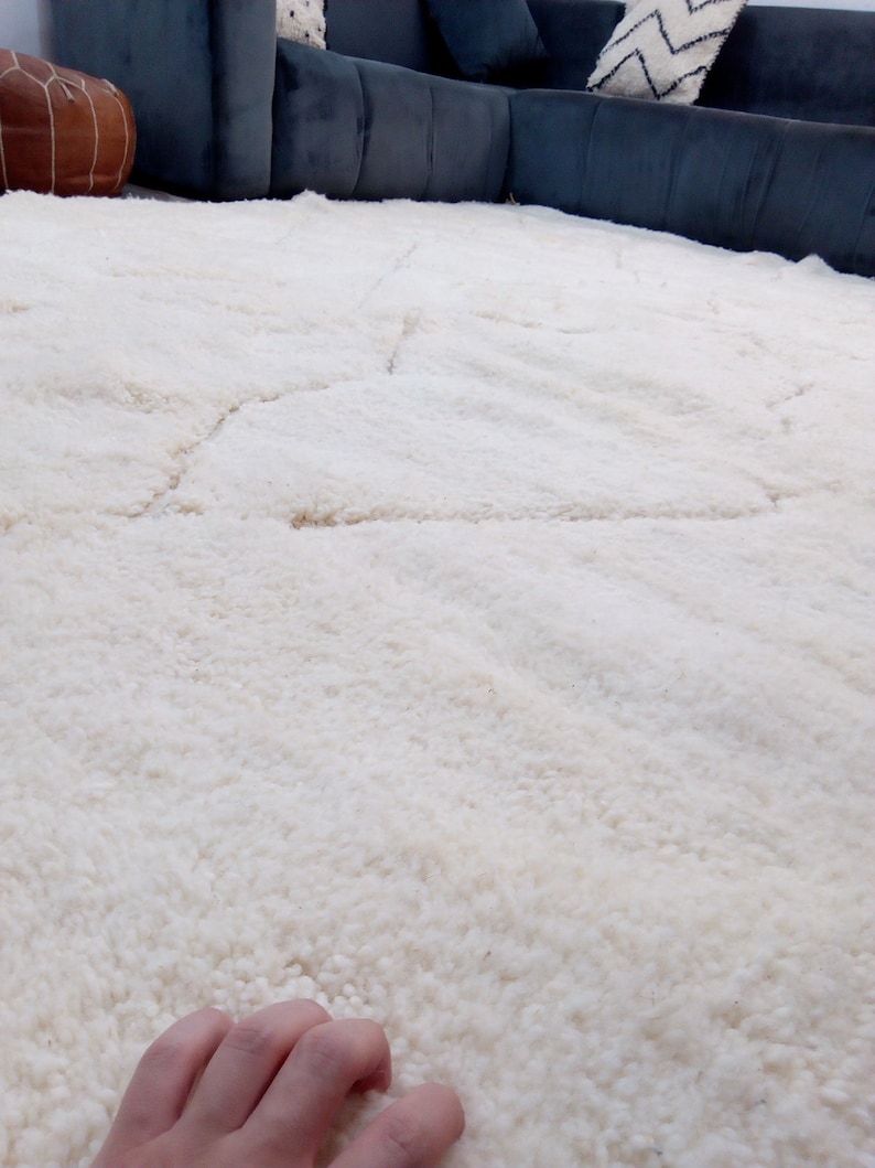 Puede incluir: Una alfombra de pelo blanco con un patr&oacute;n sutil. La alfombra es suave y esponjosa, y ser&iacute;a perfecta para una sala de estar o un dormitorio.