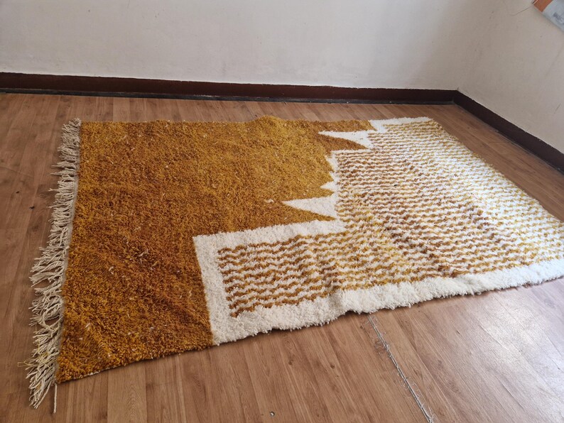 May include: A mustard yellow and white shag rug with a geometric pattern. The rug has a fringe border.