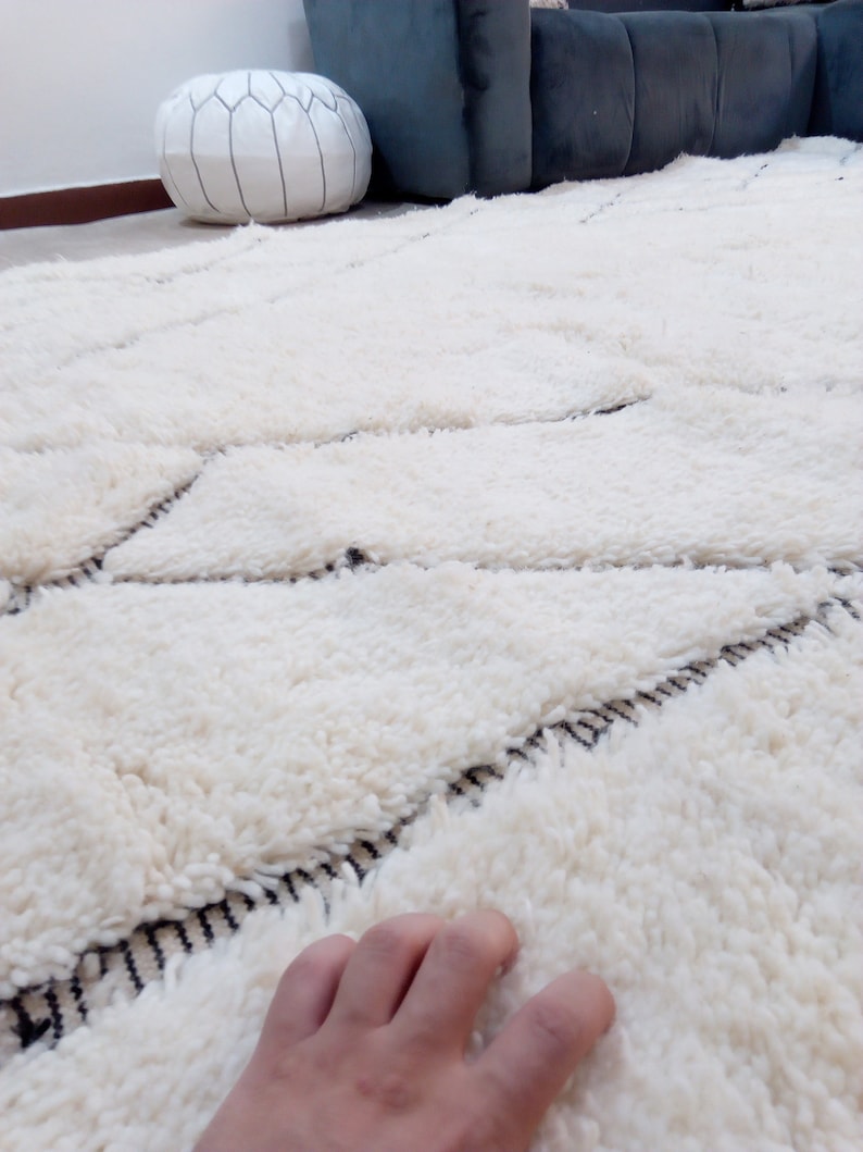 May include: A white shag rug with a geometric pattern in black. The rug is made of soft, fluffy fibers and has a luxurious feel.