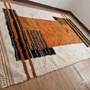 May include: A white, orange, and black geometric patterned rug with fringe on the edges.