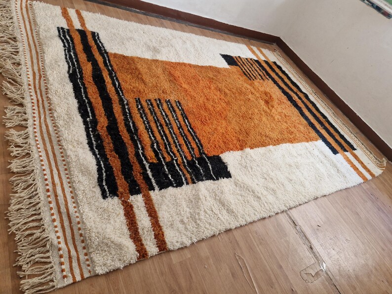 May include: A white, orange, and black geometric patterned rug with fringe on the edges.