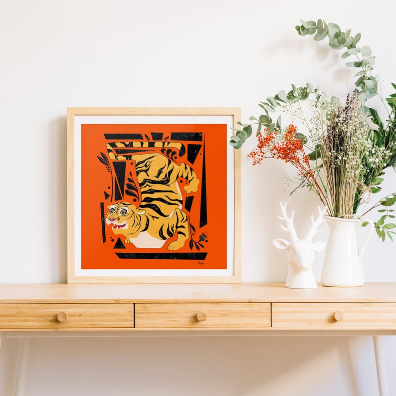 K&ouml;nnte beinhalten: Ein gerahmter Druck mit einer stilisierten Tigerillustration in Schwarz, Orange und Wei&szlig; vor einem roten Hintergrund. Der Tiger ist in einer dynamischen Pose dargestellt, umgeben von geometrischen Formen.