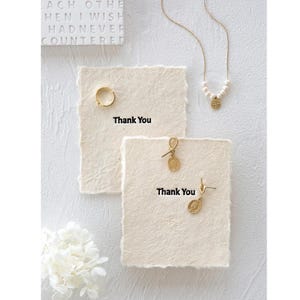 Fotografia minimalista di collana/orecchini, carta con bordo peloso, sfondo di accessori per fotografia di unghie/gioielli, ornamento decorativo, carta color crema