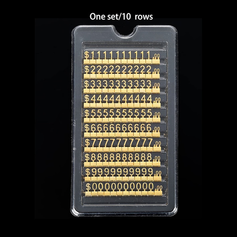 May include: A clear plastic case containing ten rows of gold-colored number stickers. Each row features a different number from 1 to 0, with a dollar sign and decimal point preceding each number. The text "One set/10 rows" is printed above the case.