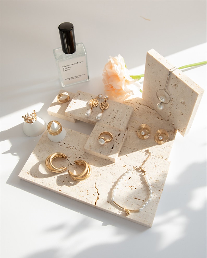 May include: A set of gold jewelry displayed on a white marble stand. The jewelry includes a necklace, earrings, rings, and a bracelet. The jewelry is made of gold and features pearls.
