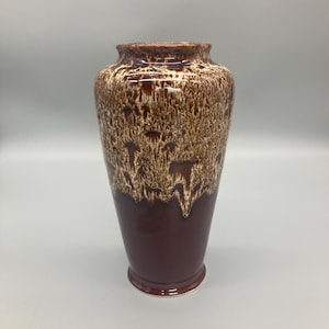 Peut inclure: Un vase en céramique marron de grande taille avec un effet de glaçure texturée et dégoulinante. Le vase a une base marron foncé qui se transforme en un motif marron clair et beige vers le haut. Le vase mesure environ 30 cm de haut.