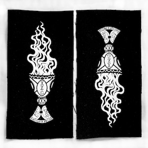 May include: Two black fabric patches with white illustrations. One depicts a chalice with flames and text, the other a bell-shaped object with flowing lines and text. The designs have a gothic or occult theme.