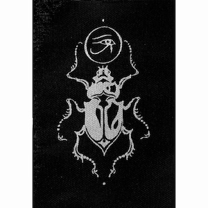 May include: A black and white embroidered patch featuring a stylized beetle with an eye of Horus symbol above it.