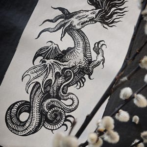 Könnte beinhalten: Schwarz-weiß-Holzschnitt eines Drachen mit einem langen, schlangenartigen Schwanz und einem grimmigen Ausdruck. Der Drache ist mit Flügeln und einer Flammenmähne dargestellt.