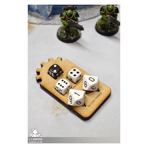May include: A wooden dice tray with five dice. Four of the dice are white with black dots and one is black with white dots. The tray has a gear design and the words "Command Points" and "Victory Points" printed on it.