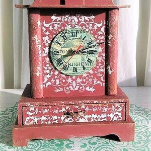 May include: A red wooden clock with a white and gold painted design. The clock face is a vintage record with Roman numerals and the text "L'Opera di Giacomo Puccini" and "La Boh&egrave;me".