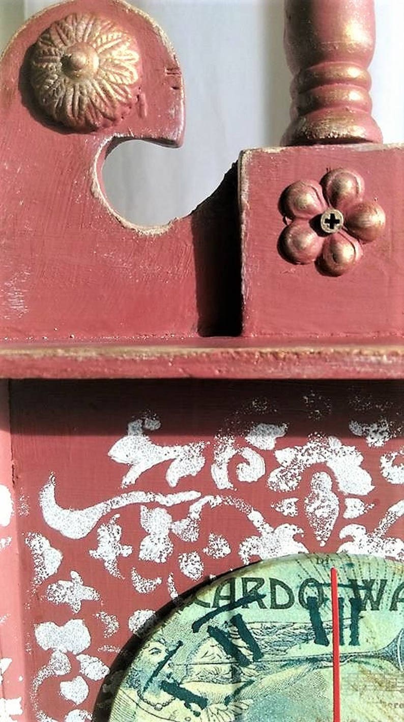 May include: A red wooden clock with a white floral design and a clock face that says "Cardova Watch".