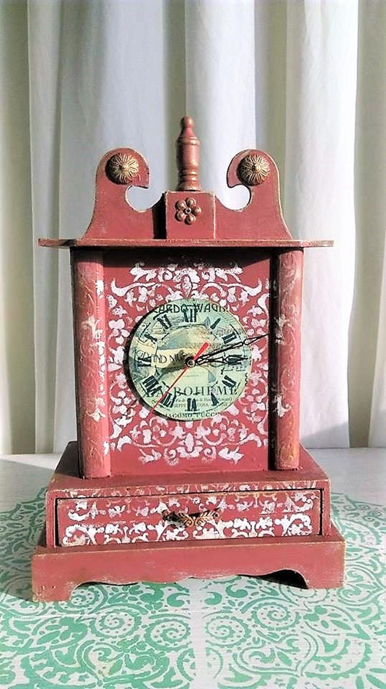 May include: A red wooden clock with a white and gold painted design. The clock face is a vintage record with Roman numerals and the text "L'Opera di Giacomo Puccini" and "La Boh&egrave;me".