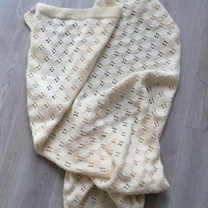 May include: A white crocheted baby blanket with a delicate openwork pattern.