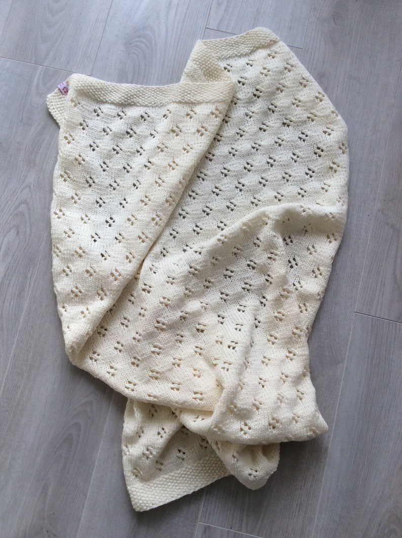 May include: A white crocheted baby blanket with a delicate openwork pattern.