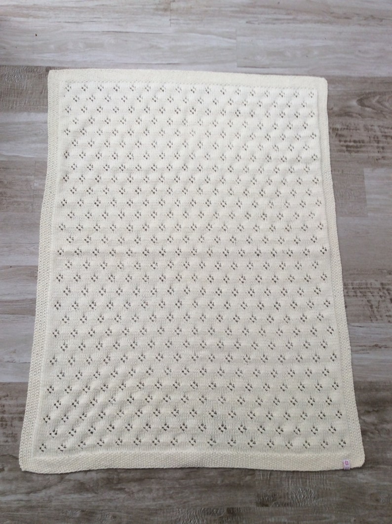 May include: A white crocheted baby blanket with a delicate openwork pattern.