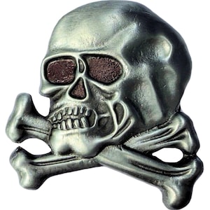 May include: A silver-colored skull with crossbones, featuring brown eye sockets. The skull has detailed teeth and a textured surface. This decorative item is likely a belt buckle or similar accessory.