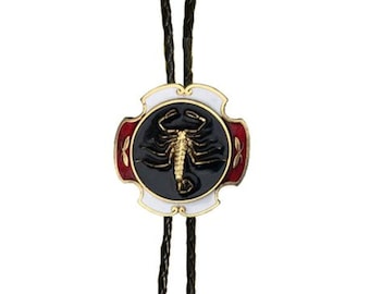 Può includere: Un bolo tie nero con un designo di scorpione dorato su un cerchio di smalto nero e bianco. La cravatta ha punte argentate con un designo ornato.