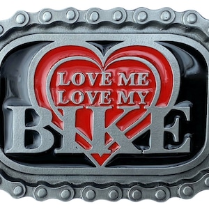 May include: A silver-colored metal belt buckle with a chain-link border. The buckle features a red heart design with the words "LOVE ME LOVE MY BIKE" in white lettering. The background is black.