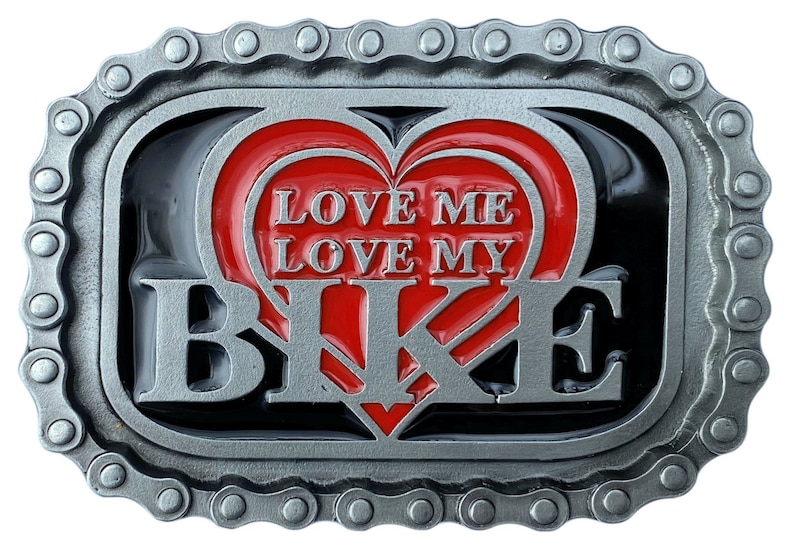 May include: A silver-colored metal belt buckle with a chain-link border. The buckle features a red heart design with the words "LOVE ME LOVE MY BIKE" in white lettering. The background is black.