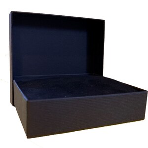 May include: A black rectangular box with a hinged lid. The box is lined with black velvet.