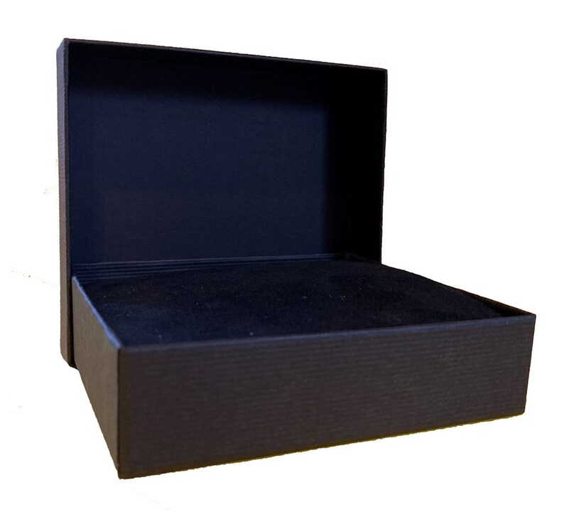 May include: A black rectangular box with a hinged lid. The box is lined with black velvet.